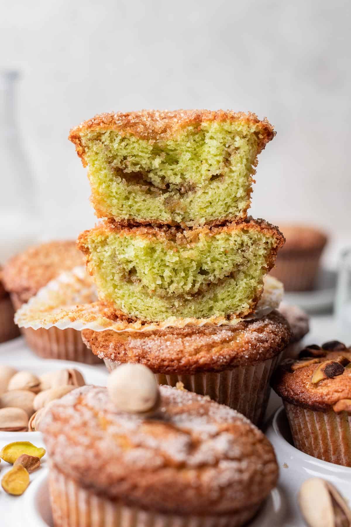 2 pistachio muffins cut in half and stacked on top of one another to show the cinnamon swirl in the middle.