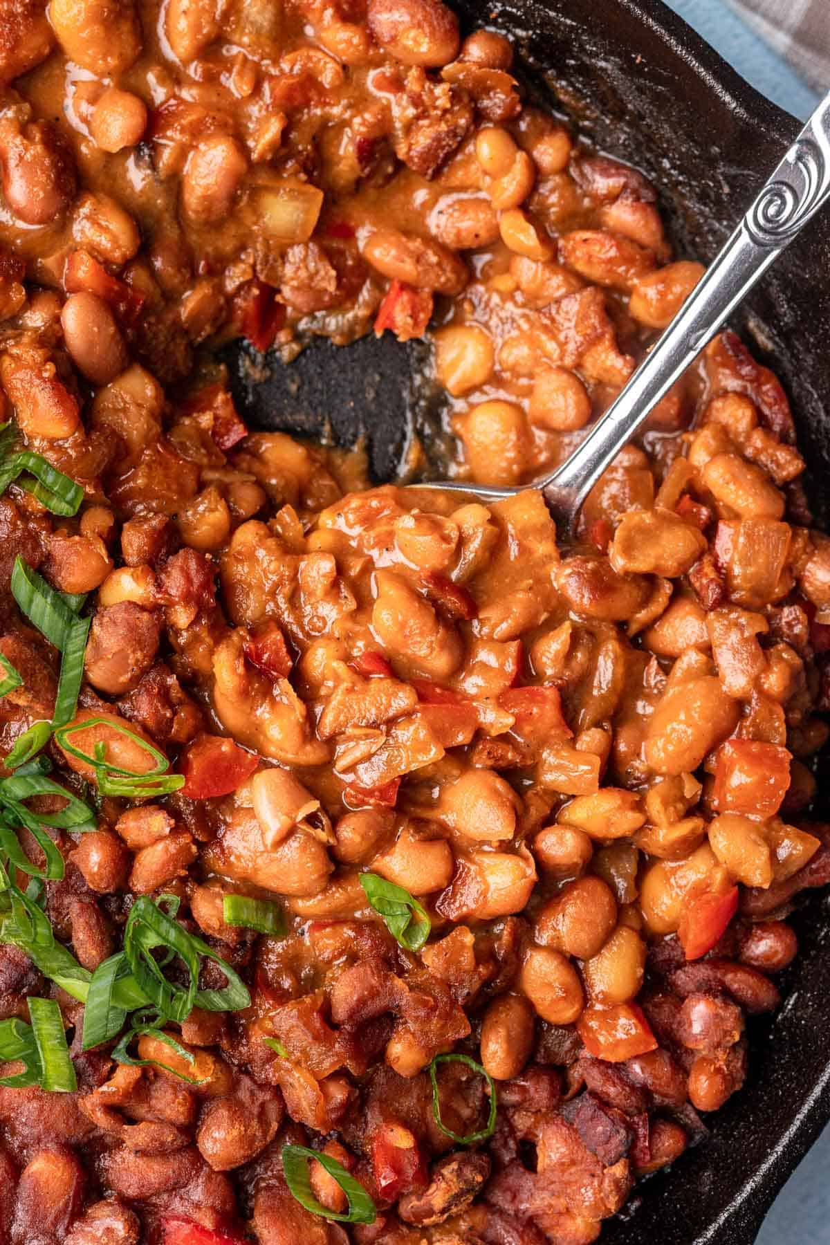Smoked baked beans scooped with a serving spoon.