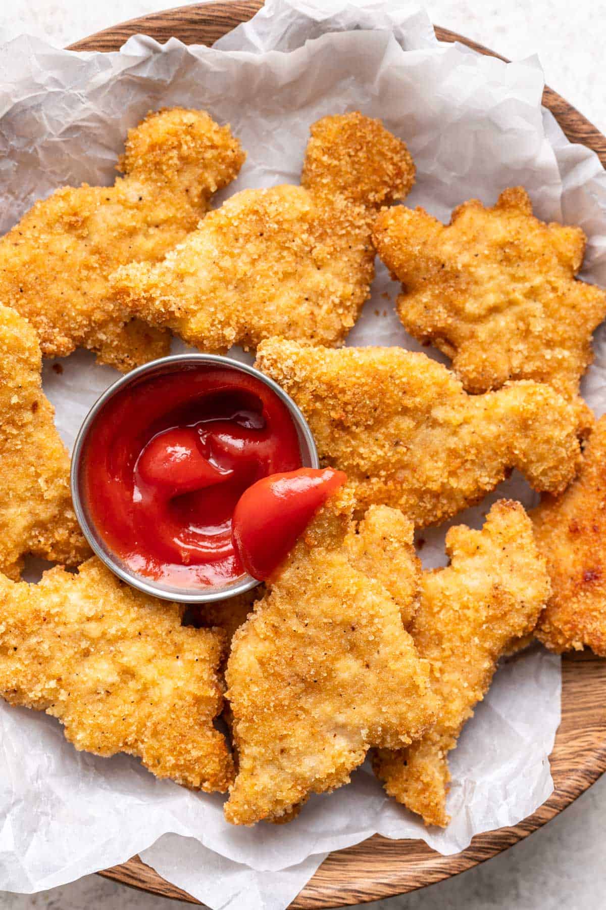 Homemade dinosaur chicken nuggets dipped in ketchup.