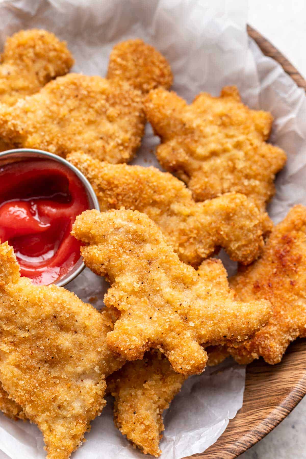 Dinosaur chicken nuggets stacked in a serving dish.