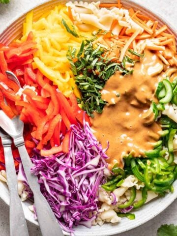 Assorted veggies on top of cooked pasta with peanut sauce on top.