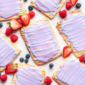 Homemade wild berry pop tarts with a purple glaze and blue swirl.