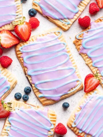 Homemade wild berry pop tarts with a purple glaze and blue swirl.