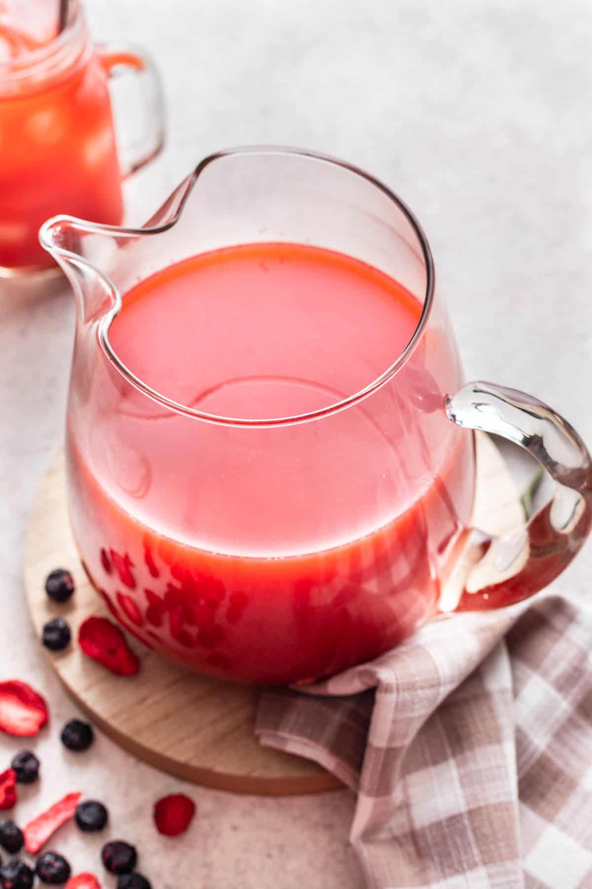 A pitcher full of homemade kool aid with freeze dried fruit next to it.