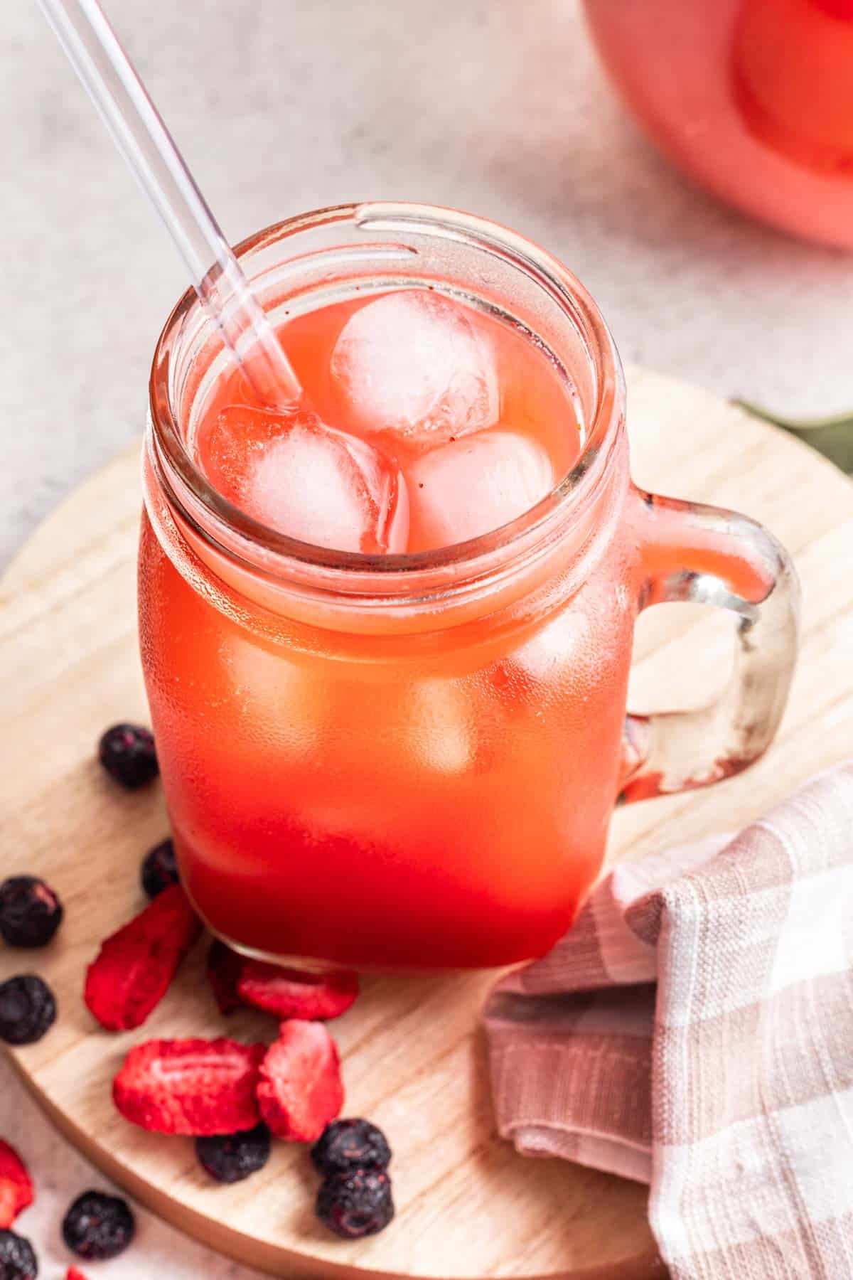Homemade dye free kool aid in a glass cup with a straw and ice.