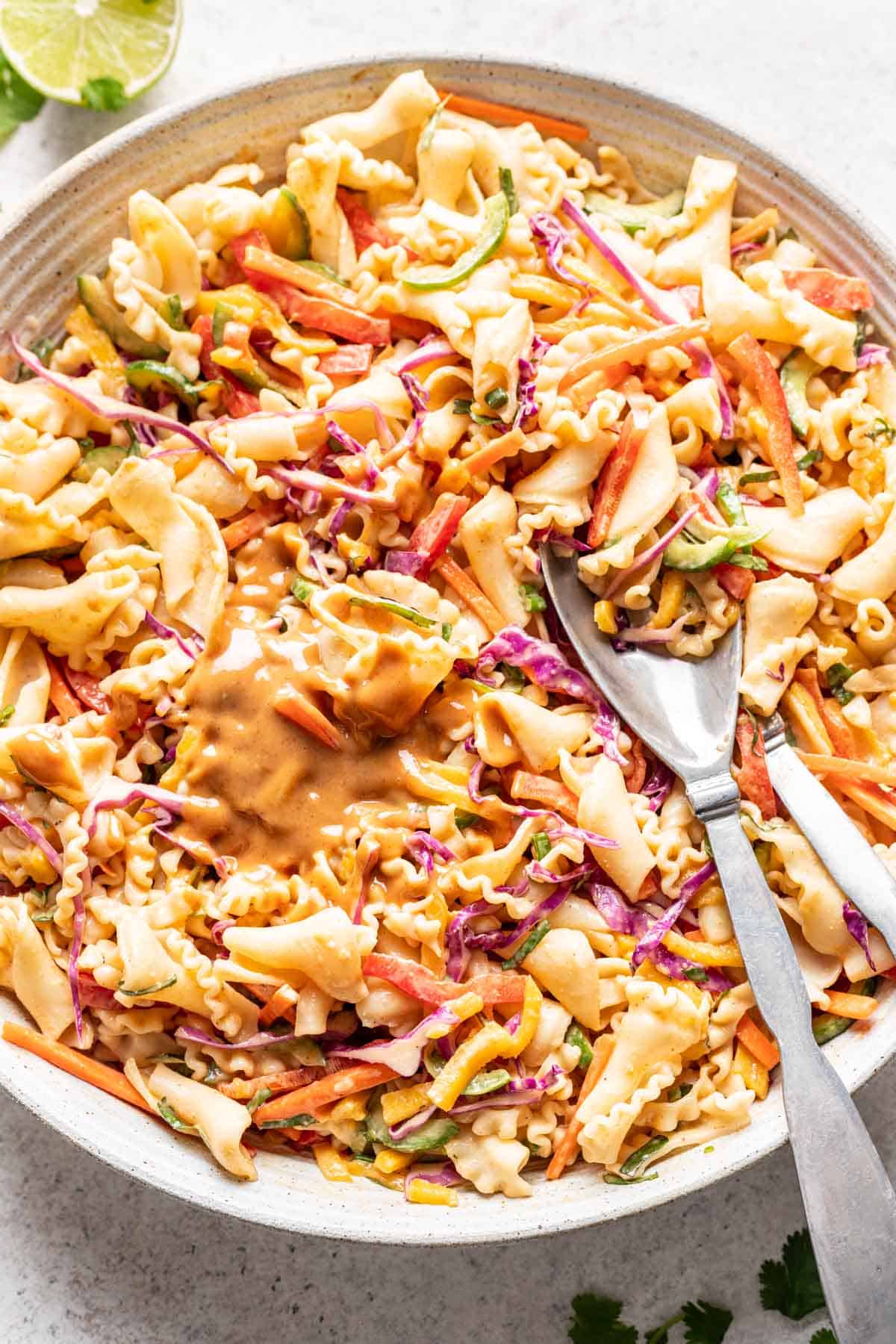 Summer roll pasta salad mixed in spicy peanut sauce in a large bowl.