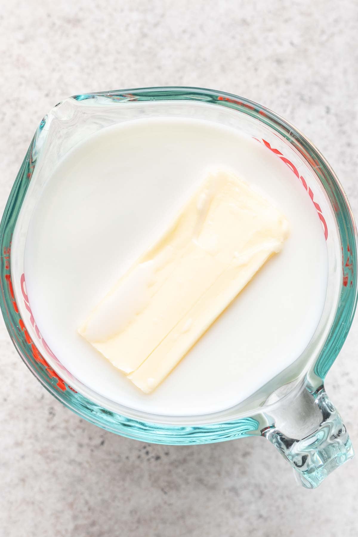 Milk and butter in a glass measuring cup.