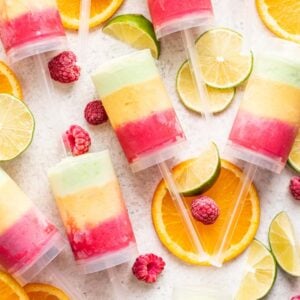 Homemade push up popsicles with raspberry, mango, and lime sherbet ice cream inside.