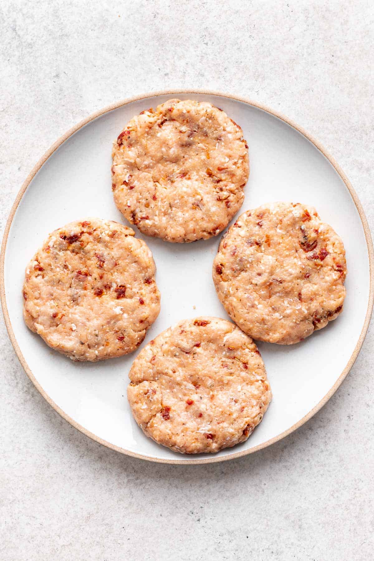 Ground chicken mixture formed into 4 hamburger patties.