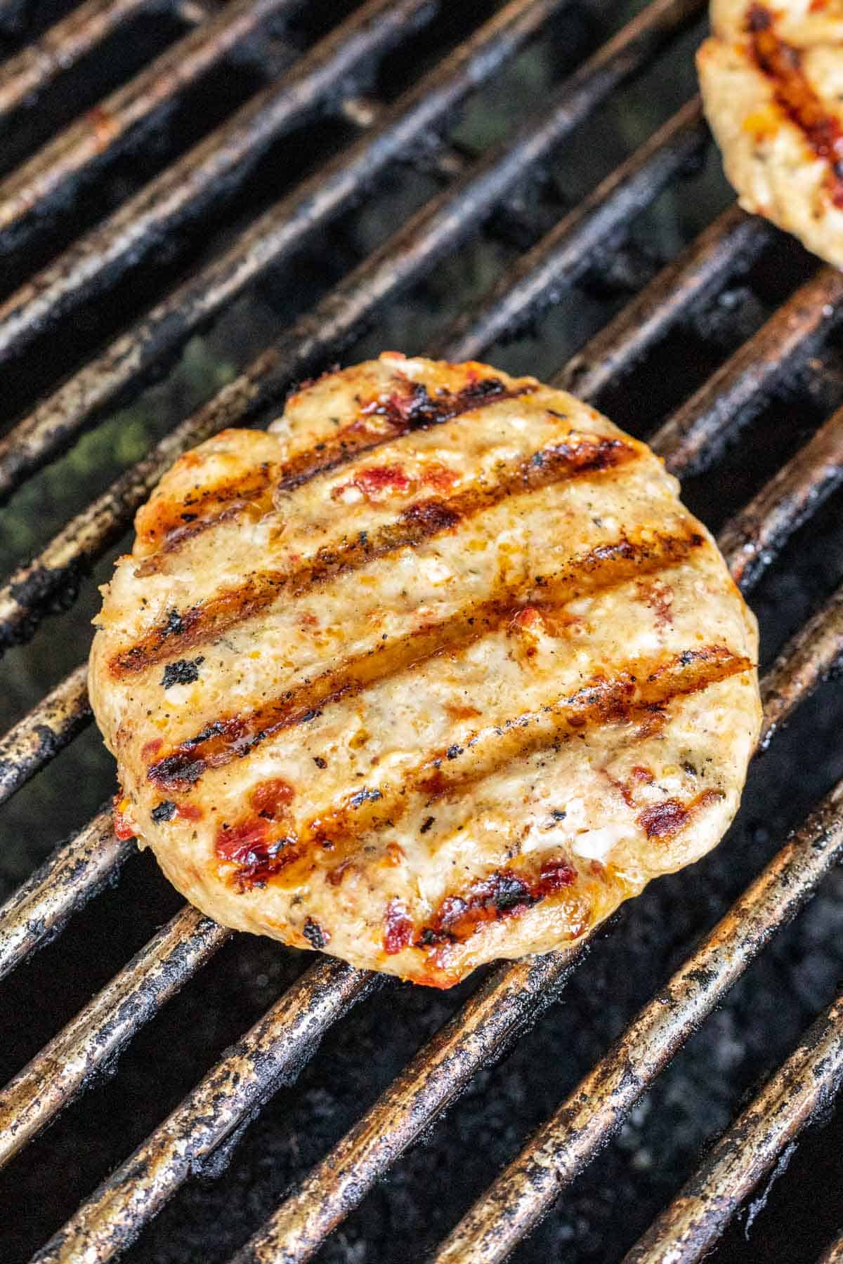 Marry Me Chicken Burger on the grill with grill marks.