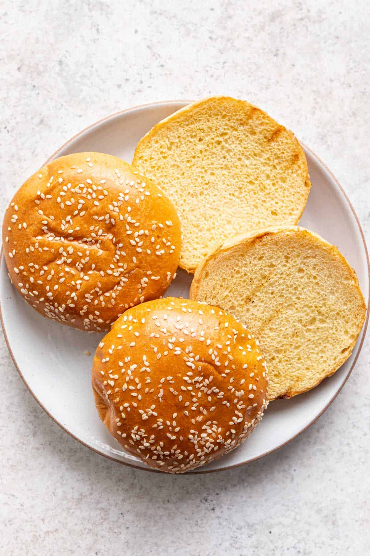 Grilled hamburger buns on a plate.
