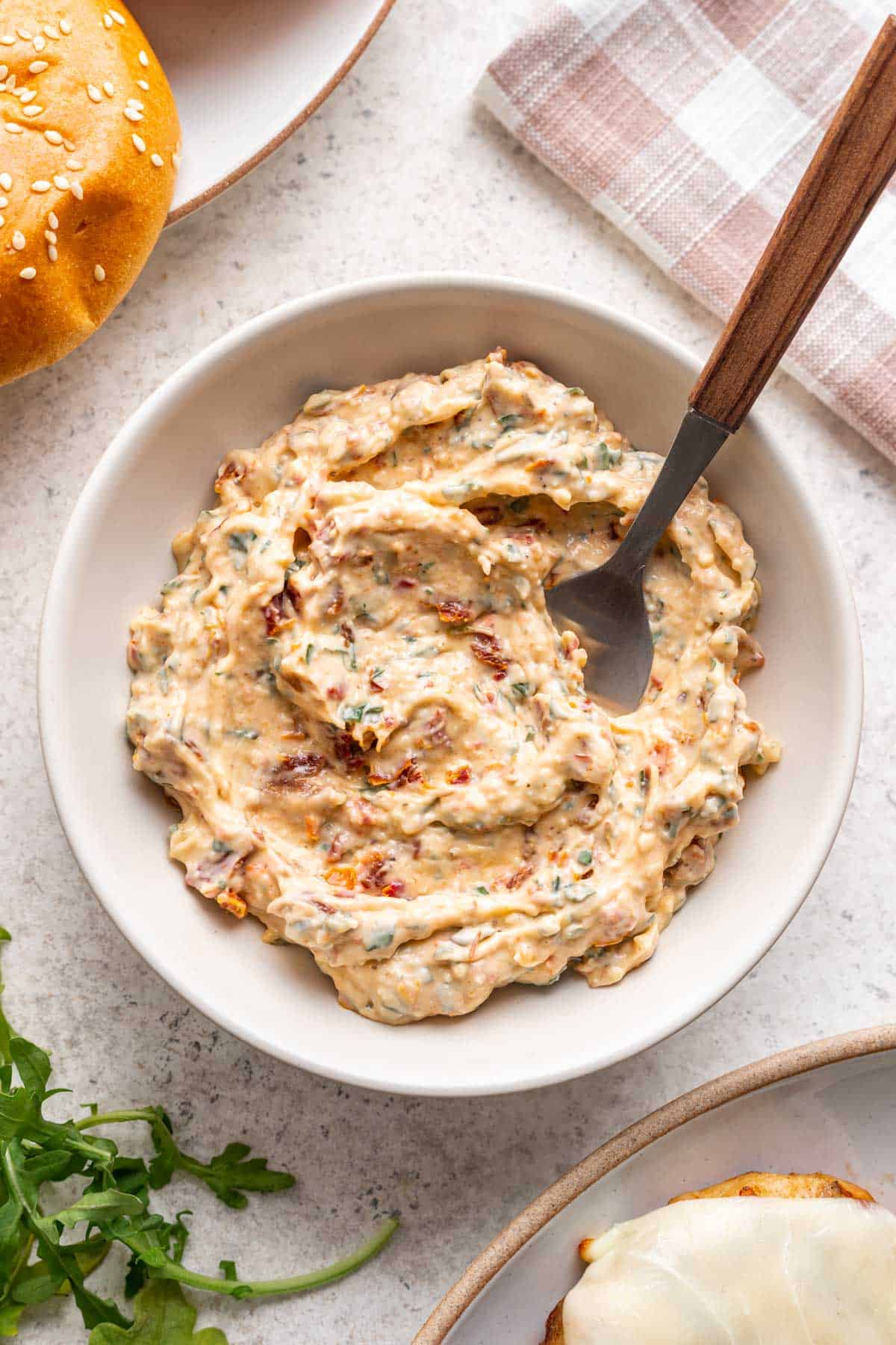 Sun dried tomato aioli in a white bowl with a serving spoon.