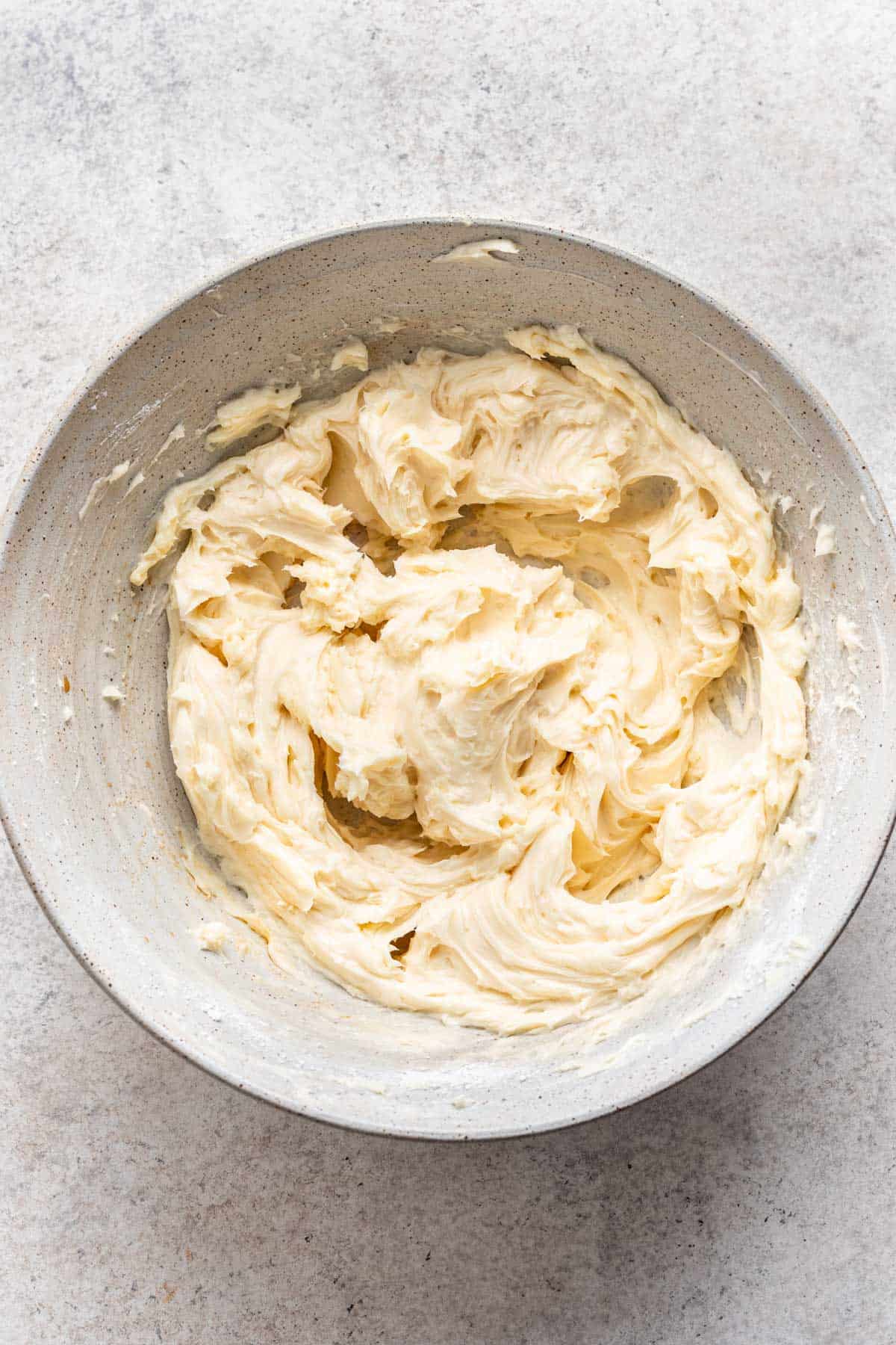 Butter beaten in a bowl with powdered sugar and vanilla extract.