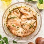 Raw chicken in a bowl with cilantro lime marinade.