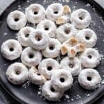 Mini powdered donuts on a black serving dish.