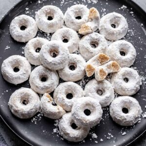 Mini powdered donuts on a black serving dish.