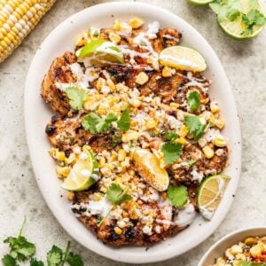 Street corn grilled chicken on a serving platter with limes and cilantro.