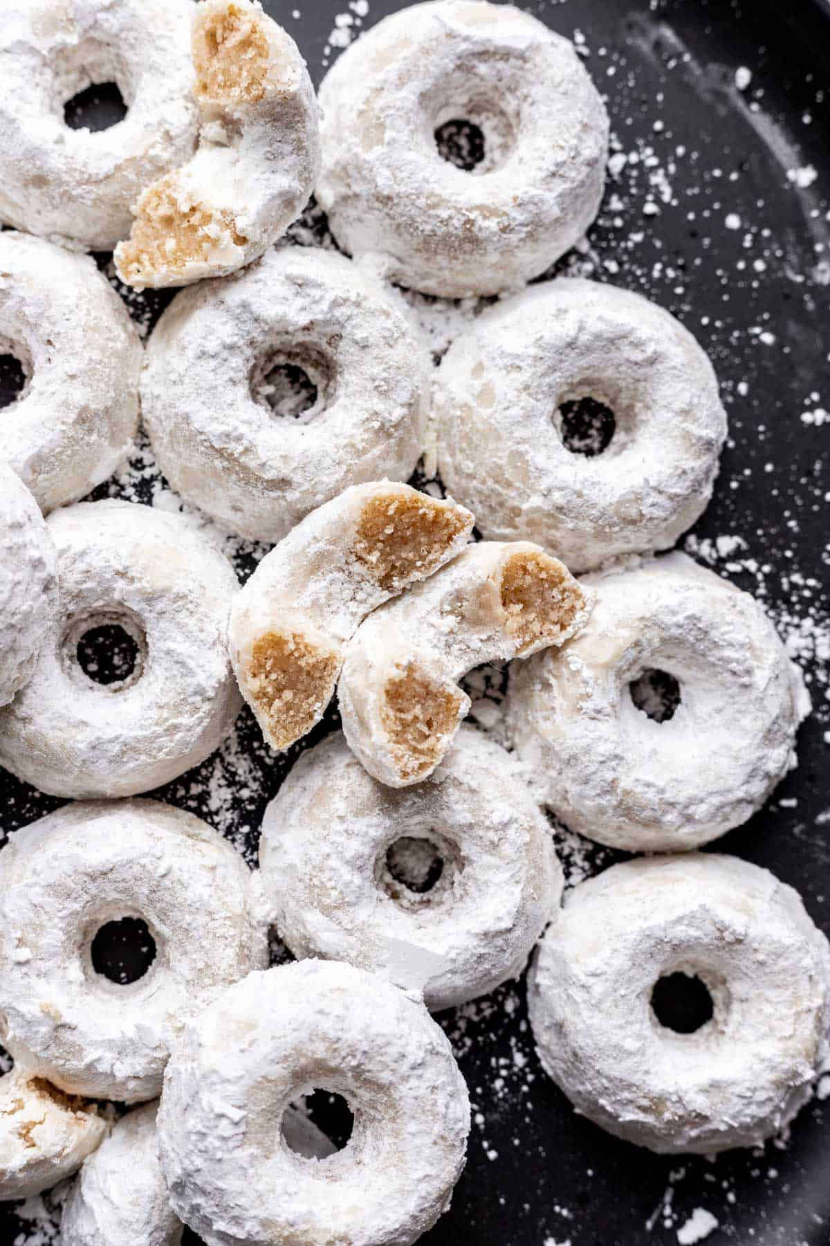 A mini powdered donut cut in half to show the fluffy inside.