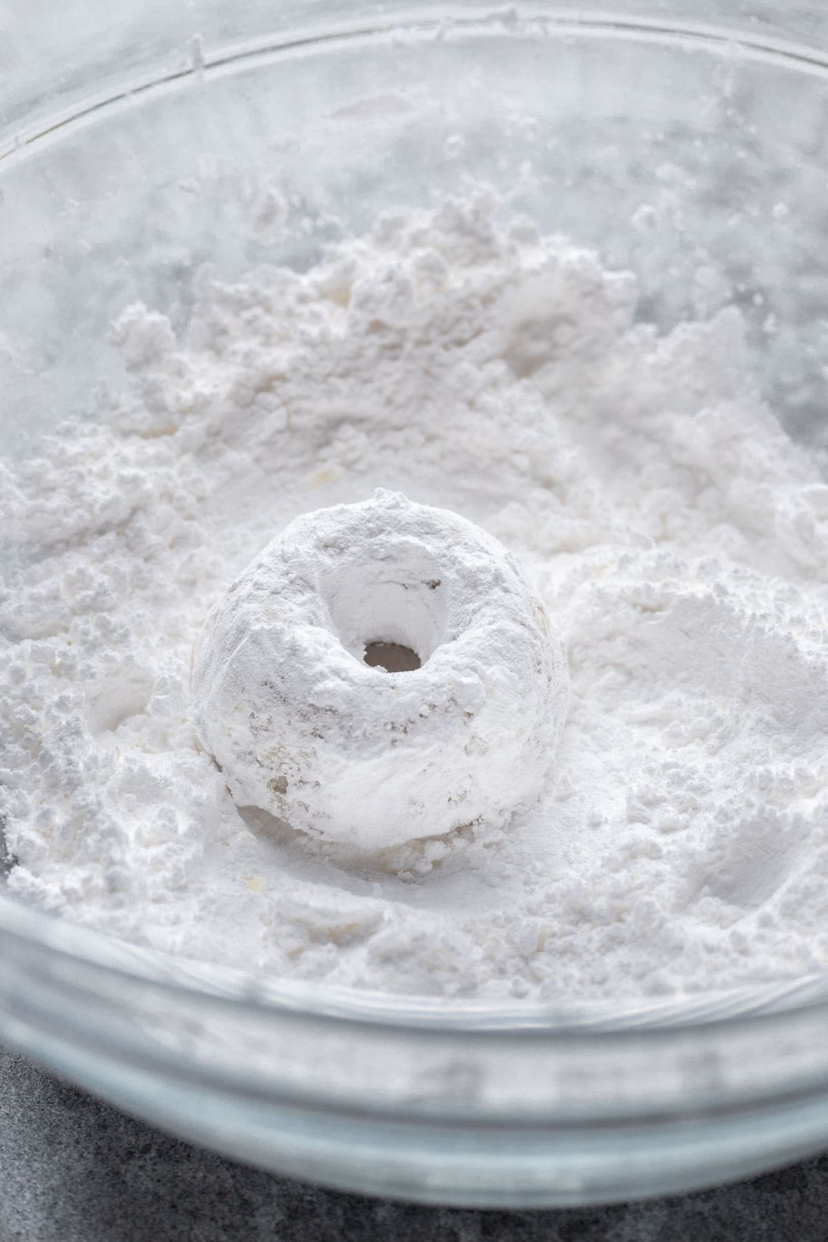 A mini donut in a bowl with powdered sugar.