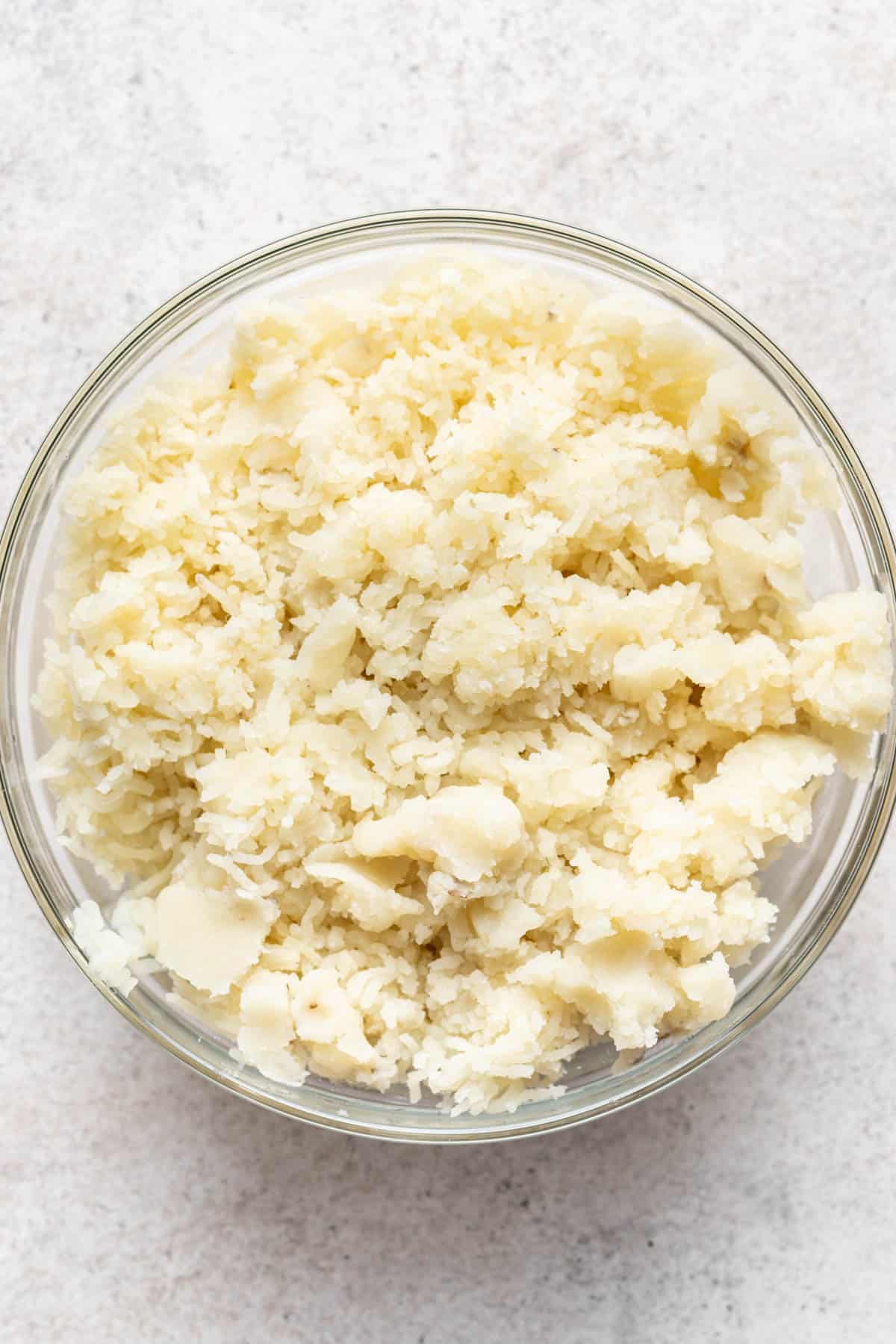 Mashed potatoes riced into a glass bowl.