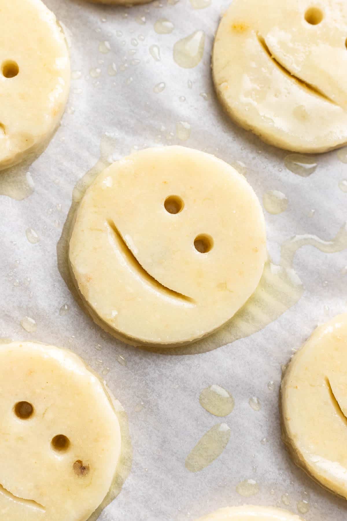 Homemade smiley potato on a baking sheet sprayed with oil.