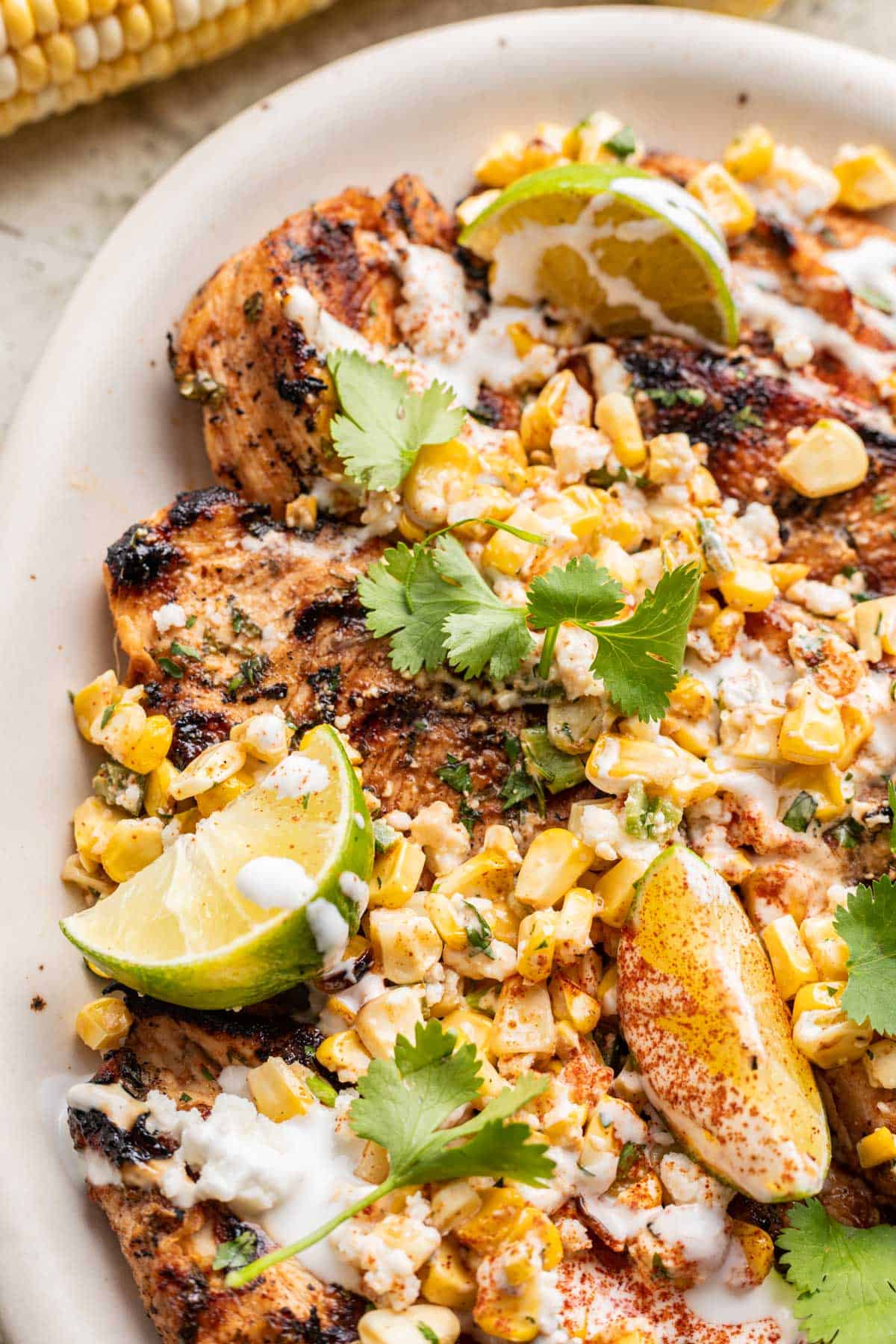 Cilantro lime grilled chicken on a platter with street corn salsa on top.