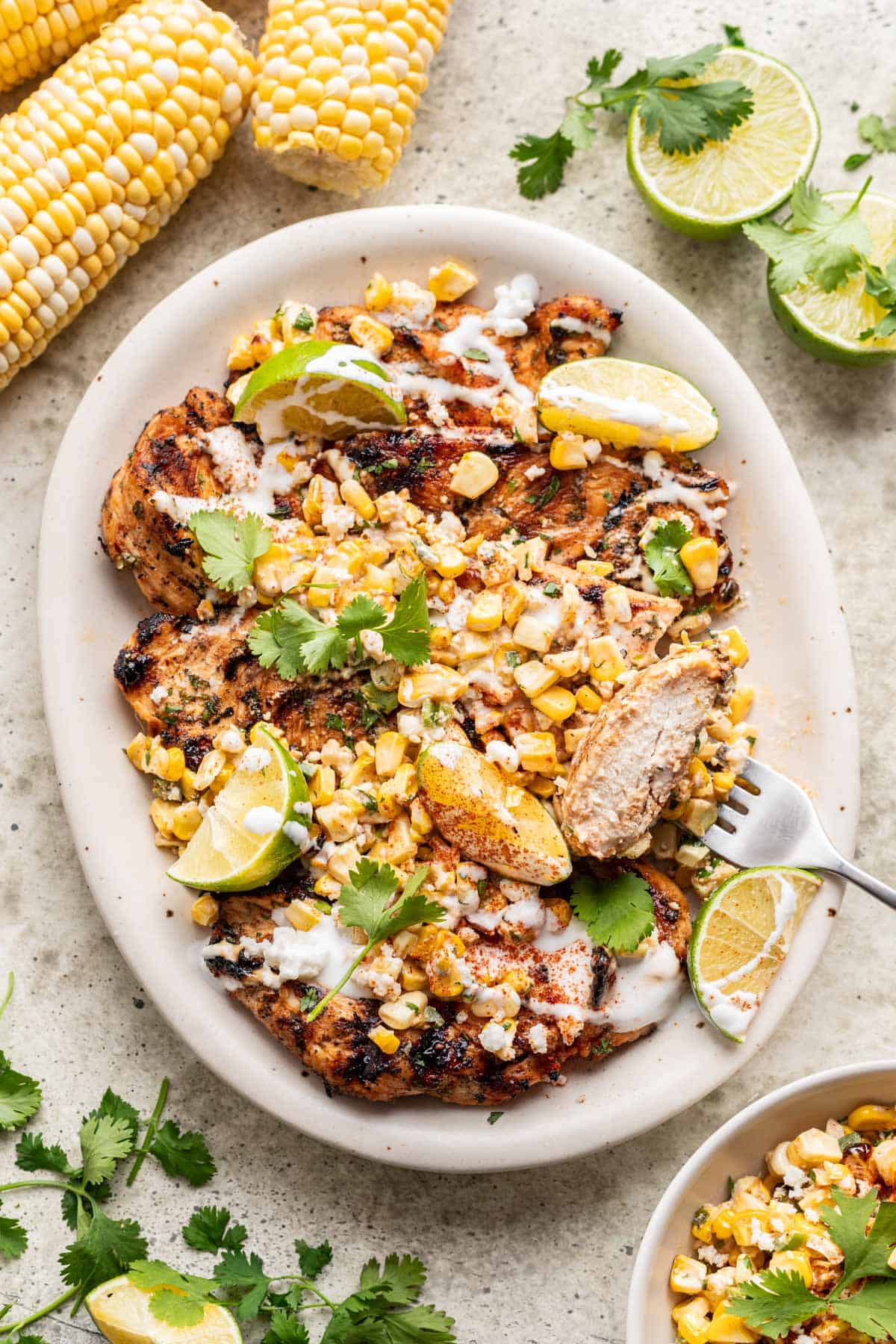 Street corn grilled chicken on a serving platter with a fork.