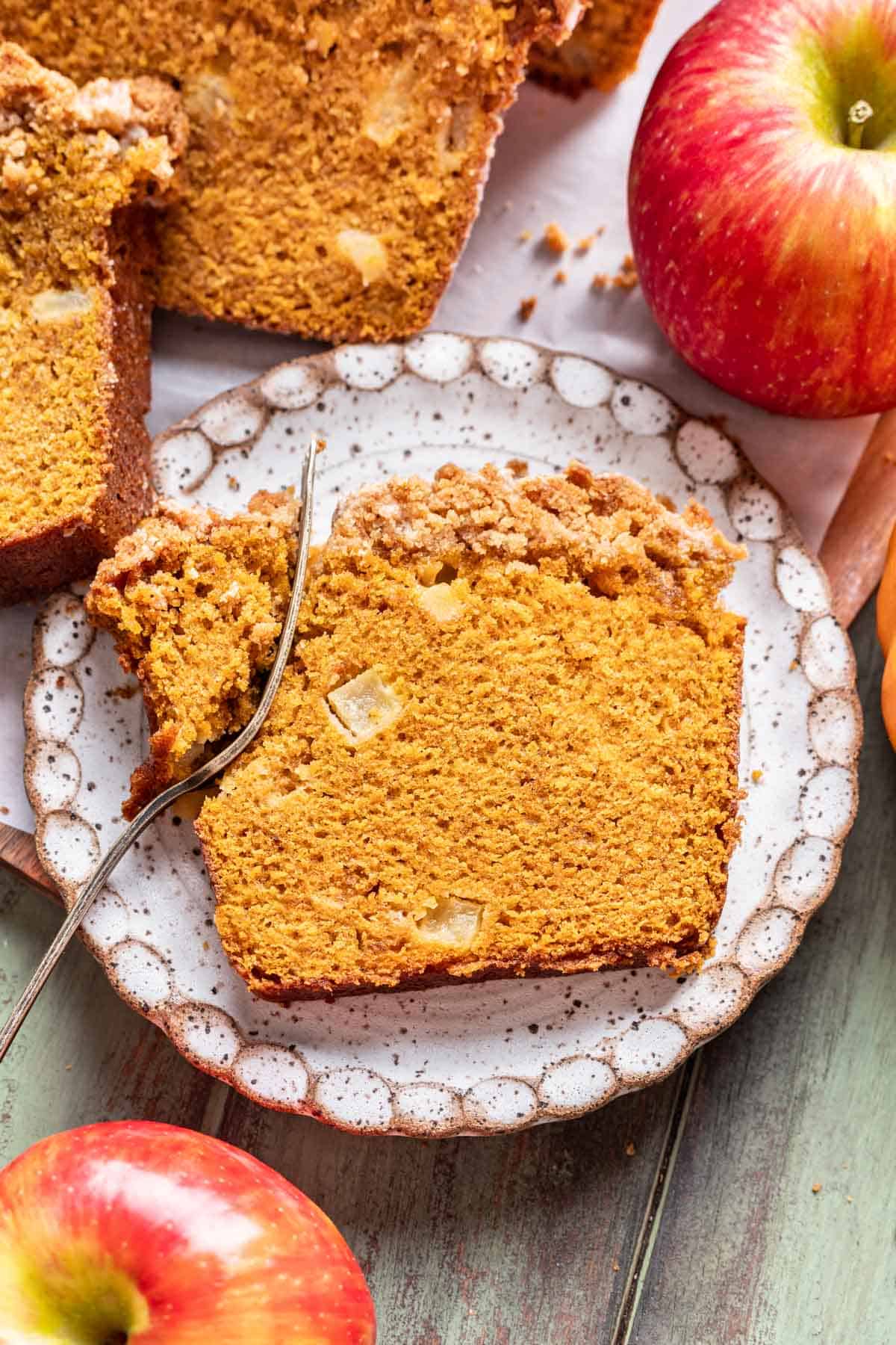 Apple pumpkin bread on a white plate with a fork taking a piece out.