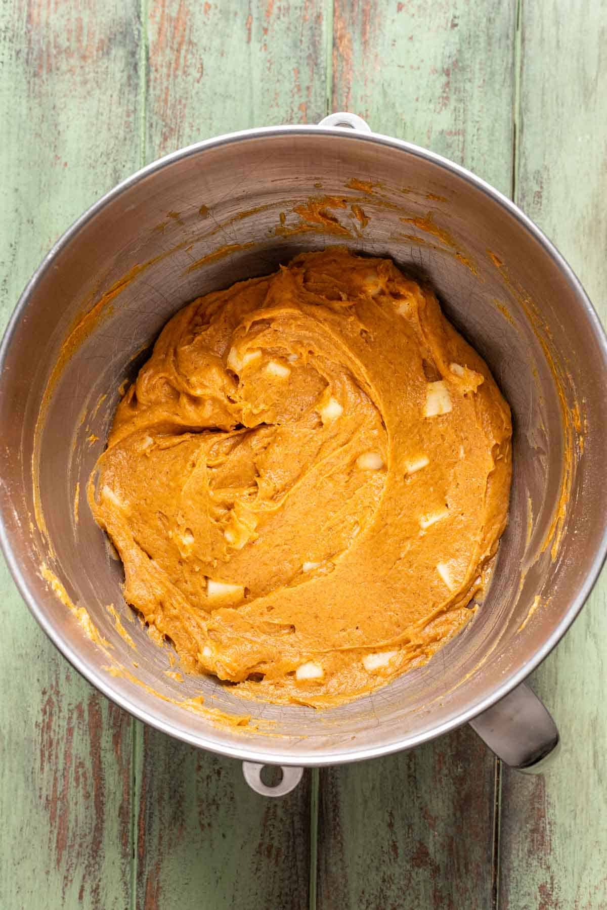 Apples mixed into the pumpkin bread batter in the bowl.