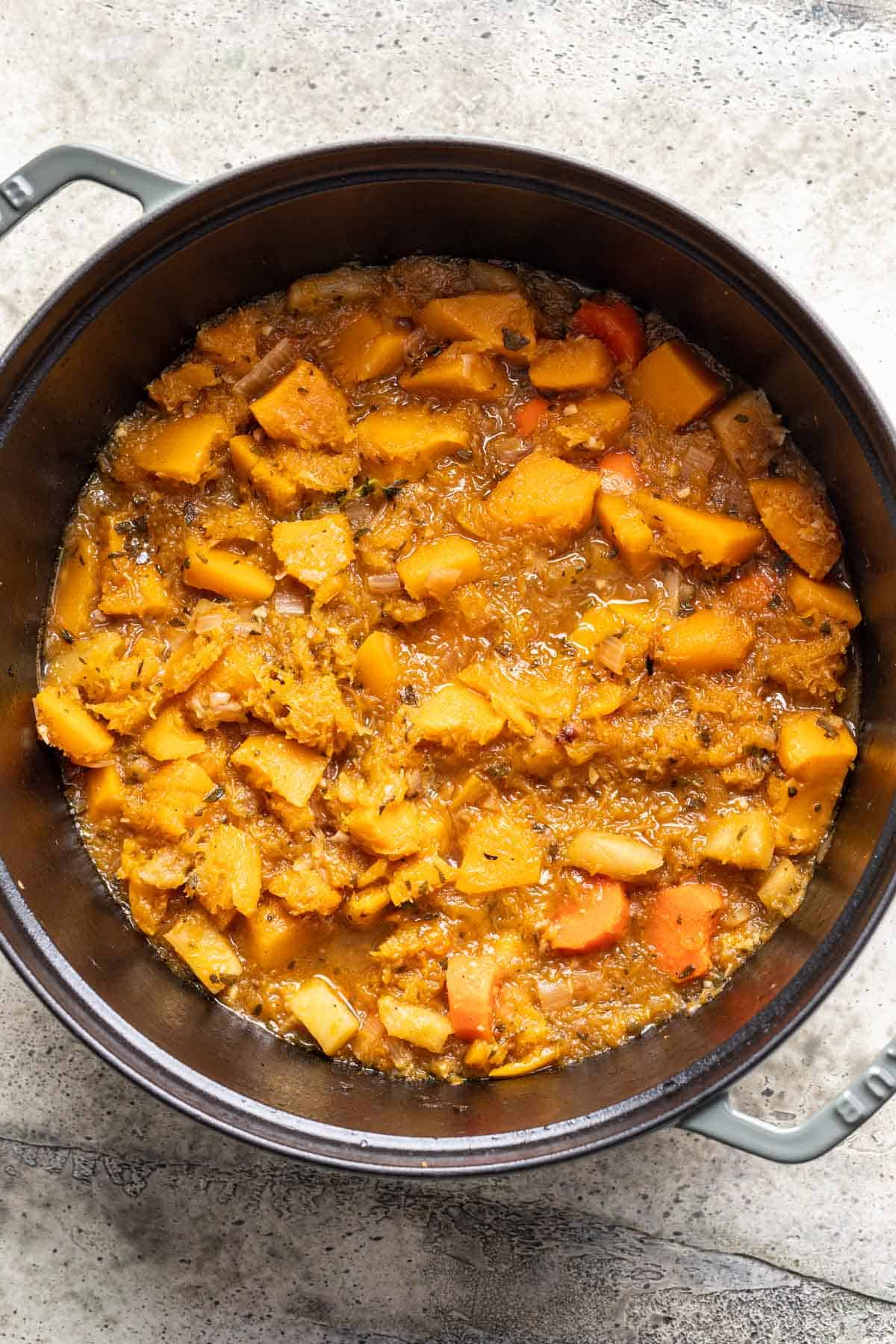 Fork tender butternut squash, carrots, and apples in a pot. 