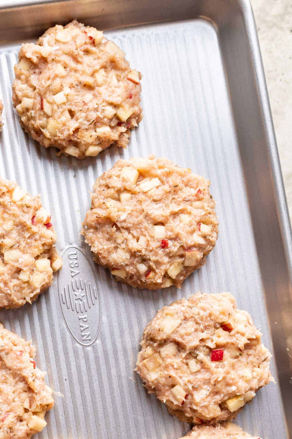 Raw chicken and apple breakfast sausages on a tray.