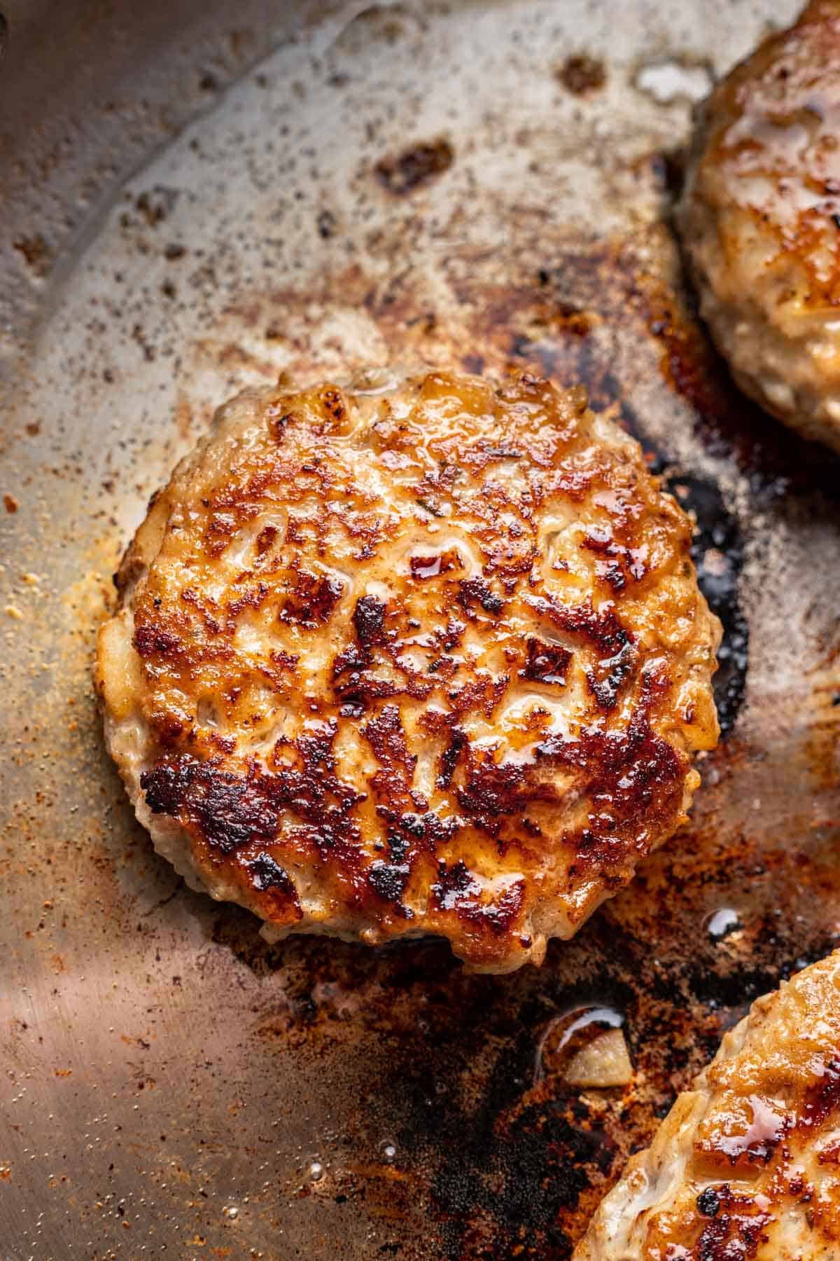 Chicken and apple breakfast sausage cooking in a skillet.