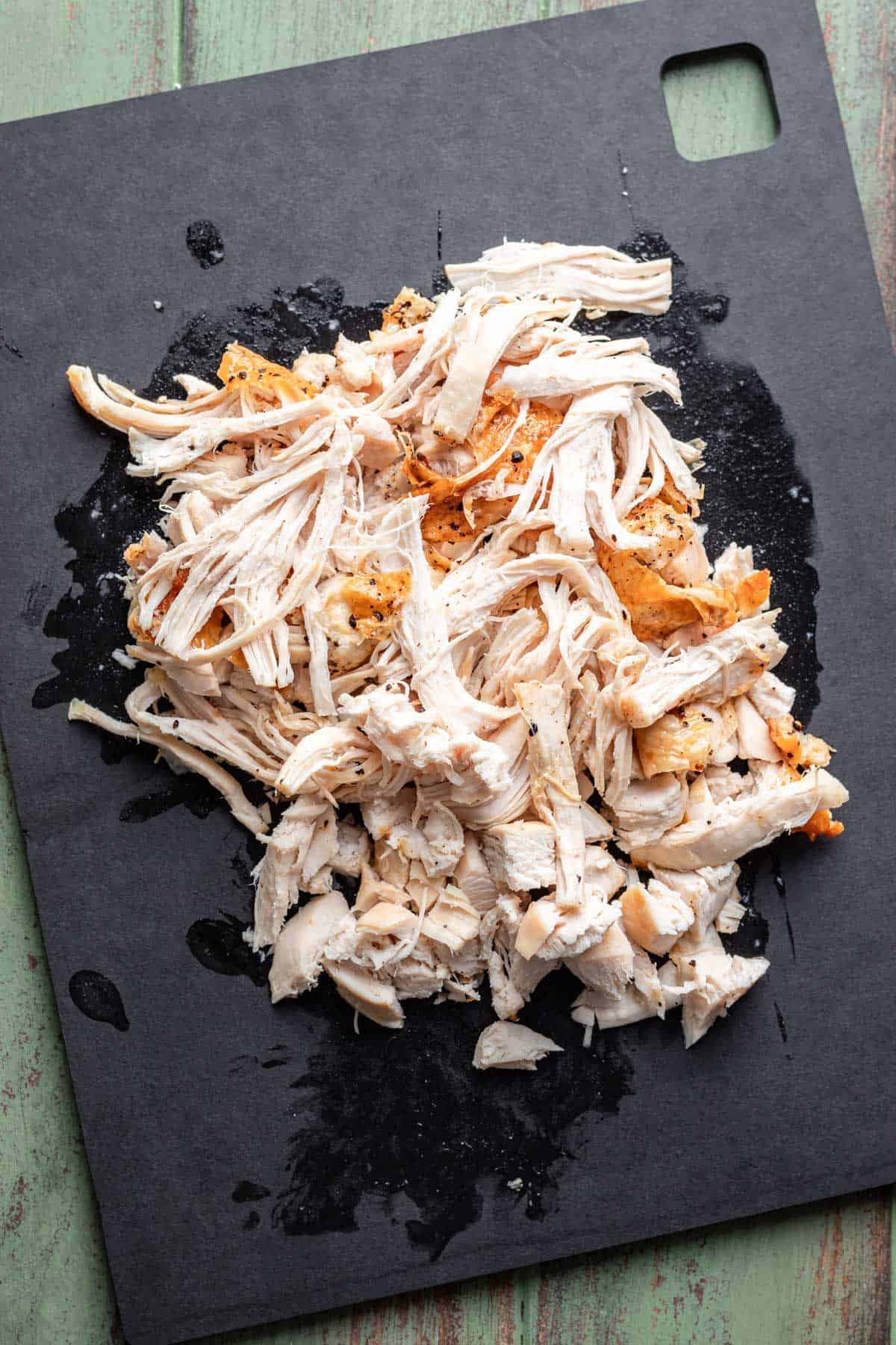 Shredded cooked chicken on a cutting board.