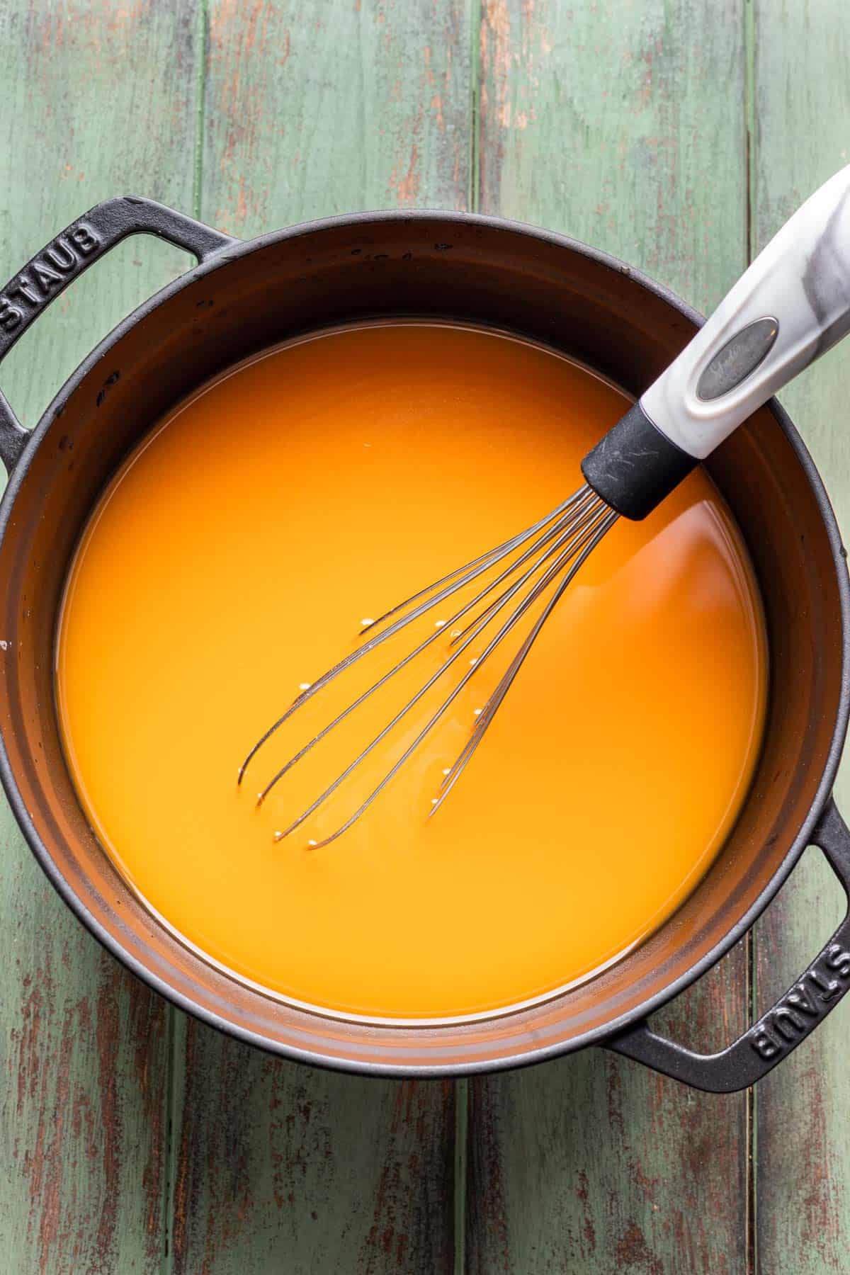 Pumpkin and broth whisked together in a pot.