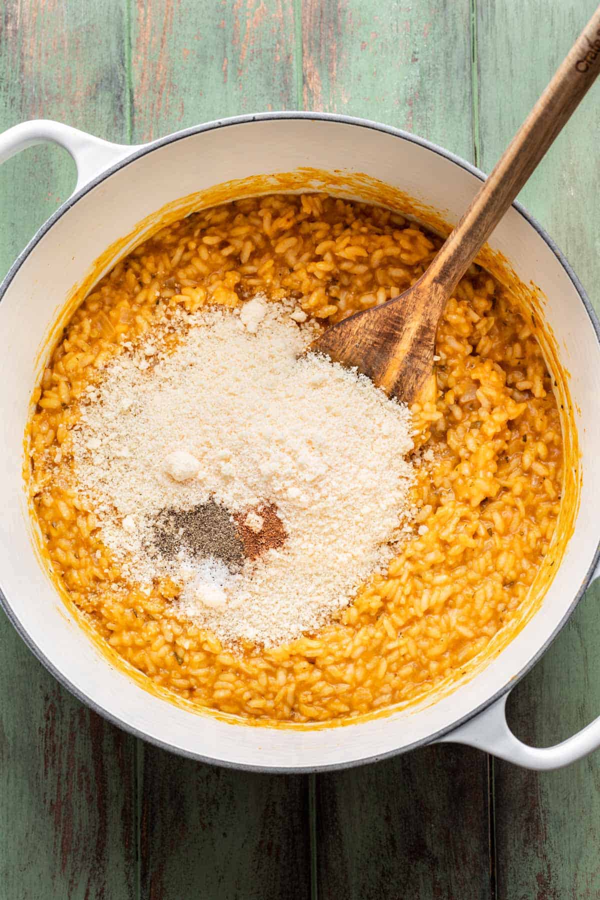 Parmesan cheese, nutmeg, salt, and pepper added to the cooked risotto in the pot.