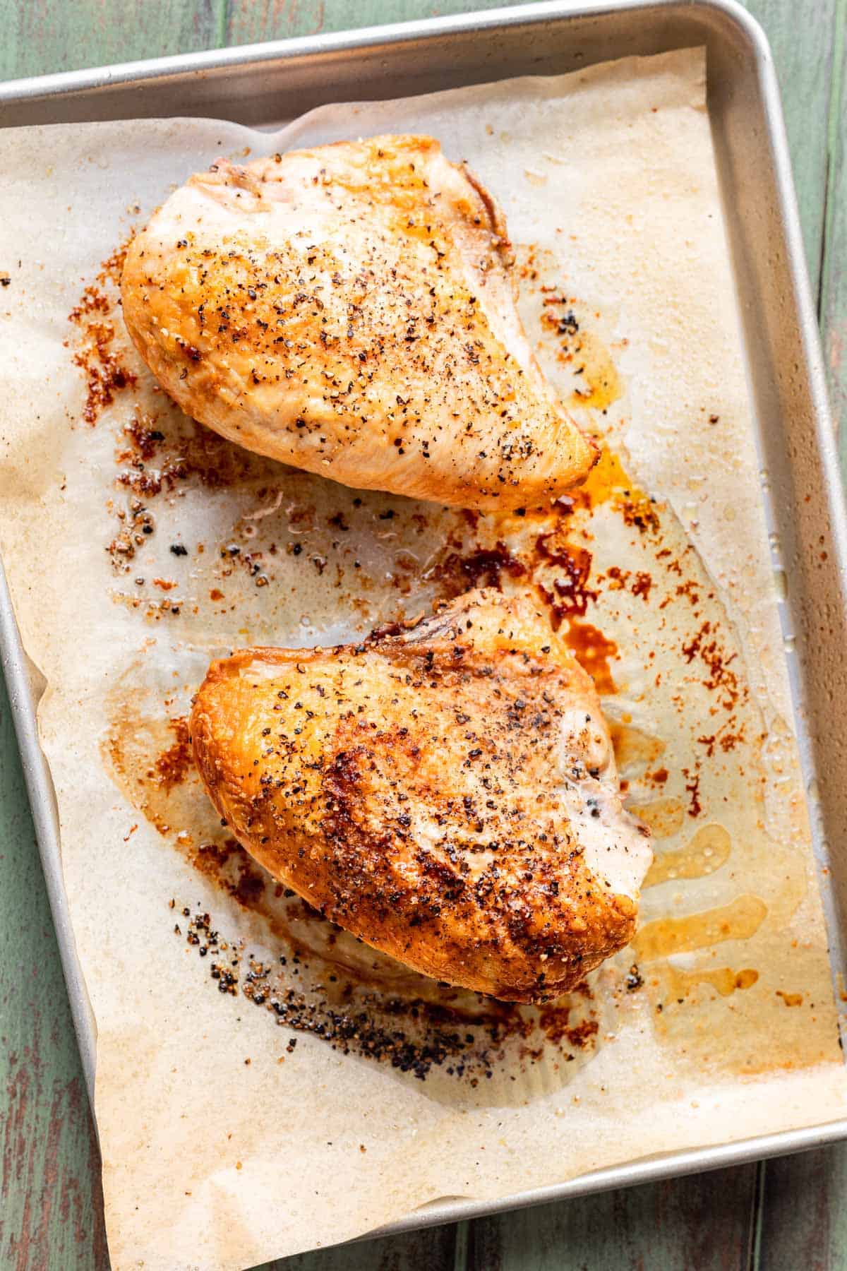 Roasted chicken breasts on a baking sheet.