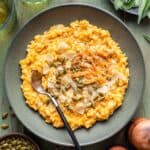 Chicken and Pumpkin Risotto in a green bowl topped with pepitas and shaved parmesan cheese.