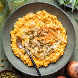Chicken and Pumpkin Risotto in a green bowl topped with pepitas and shaved parmesan cheese.