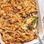 Green bean and artichoke casserole in a baking dish with a serving spoon.
