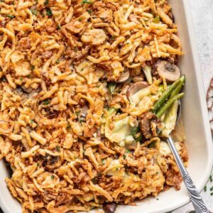 Green bean and artichoke casserole in a baking dish with a serving spoon.