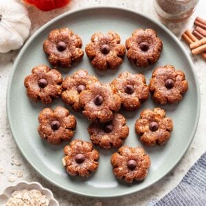 Pumpkin shaped bliss balls on a green plate.