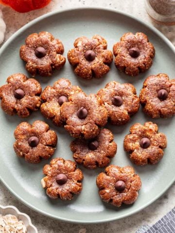 Pumpkin shaped bliss balls on a green plate.