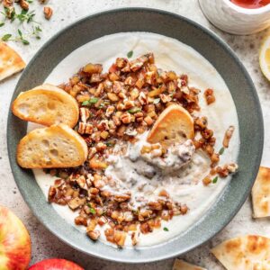 Whipped feta in a green bowl, topped with apple and pecan topping and toasted bread.