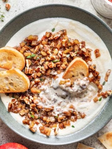 Whipped feta in a green bowl, topped with apple and pecan topping and toasted bread.