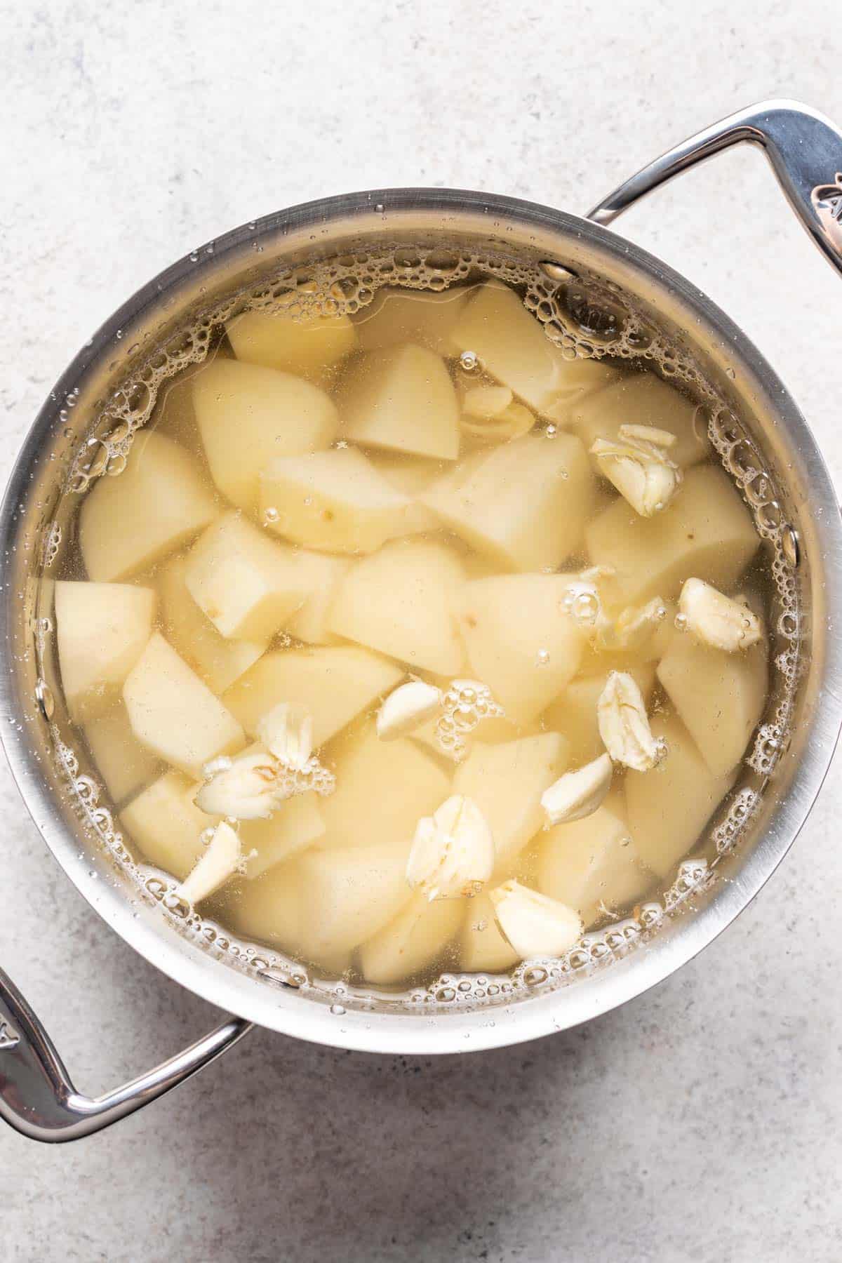 Water added to the potatoes and garlic in a pot.
