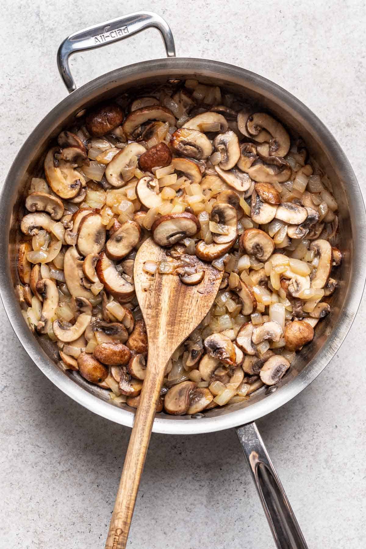 Mushrooms and onions sautéed in a skillet.