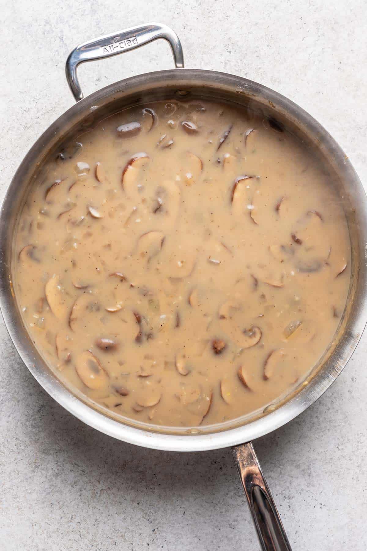 Broth, seasonings, and milk added to the skillet with the mushrooms.
