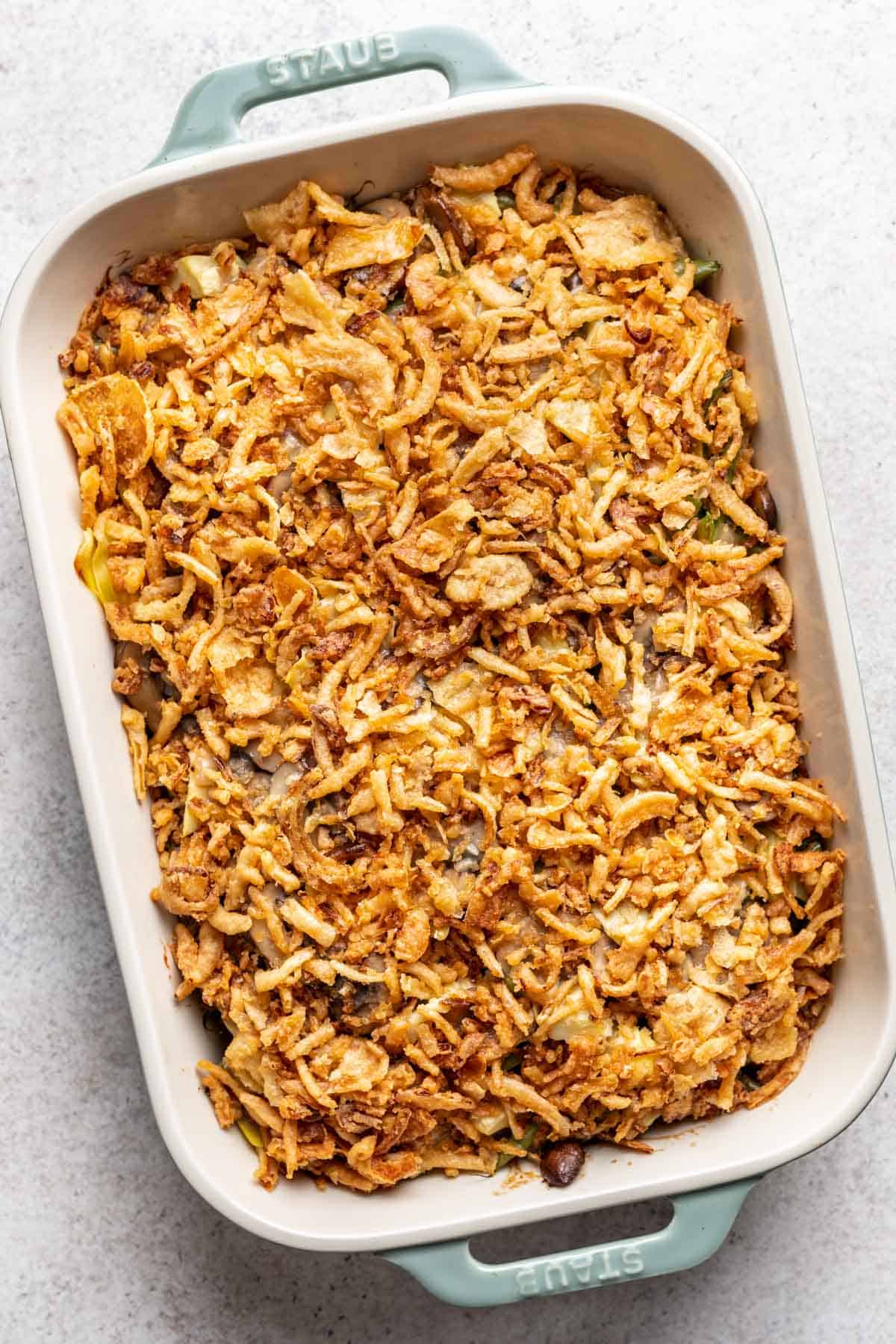 Green bean and artichoke casserole in a baking dish topped with fried onions.