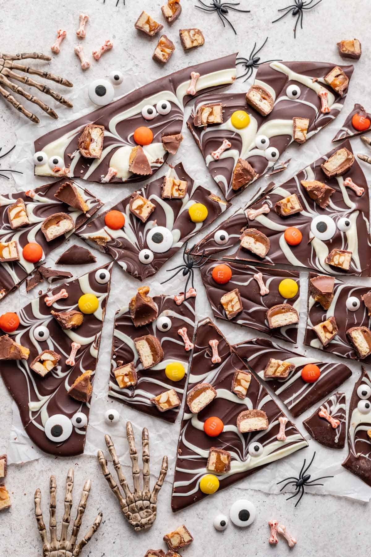 Halloween candy bark broken into many pieces on a white backdrop.