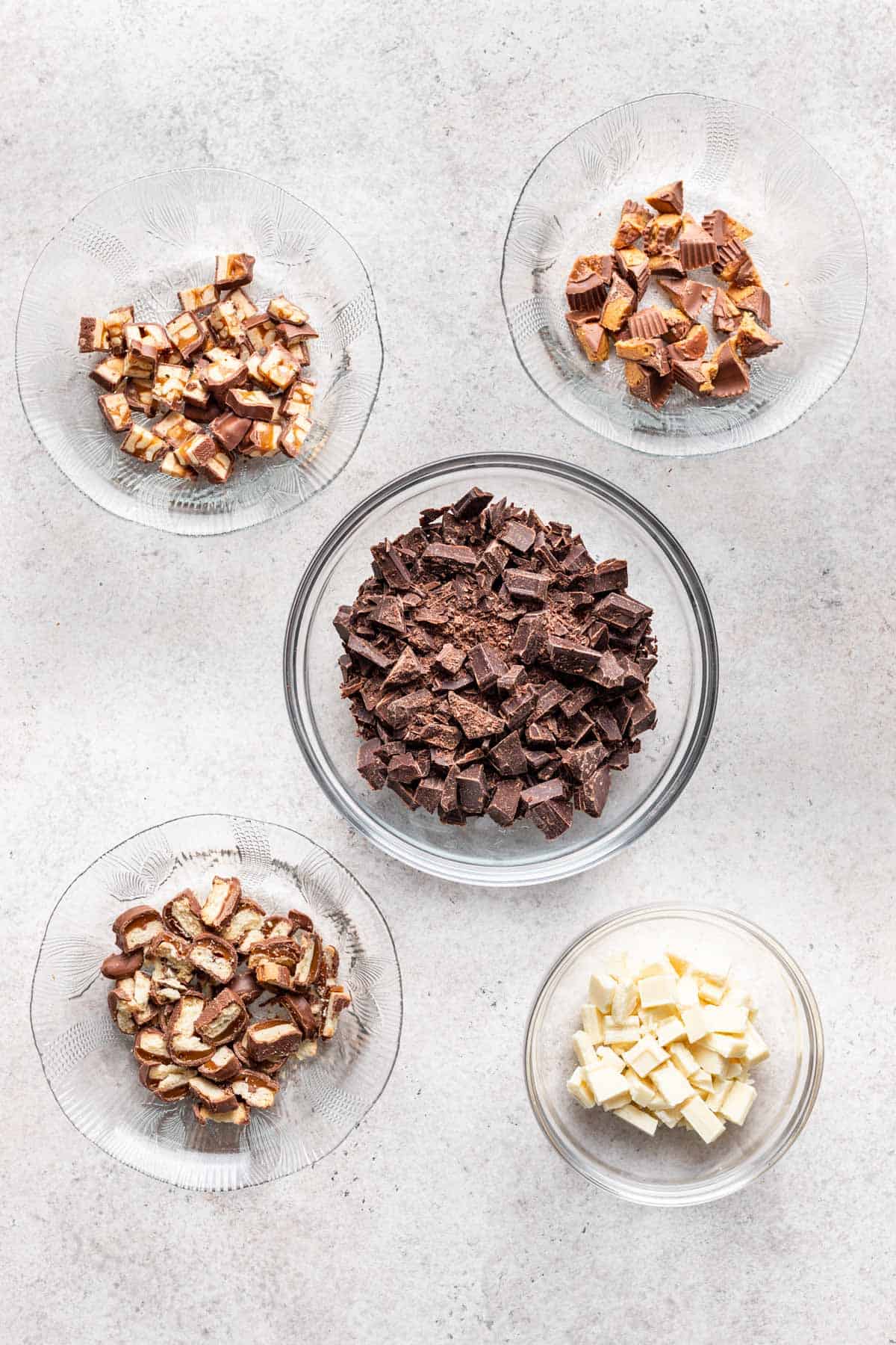 Chopped chocolate and candy bars in separate bowls.